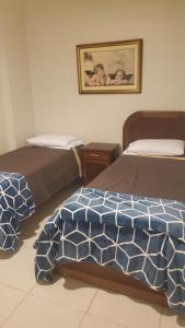 a bedroom with two beds and a picture on the wall at Guarujá - Praia do Tombo - Apartamento in Guarujá +9 photos