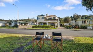 une table et deux chaises sur l'herbe devant une maison dans l'établissement Beachfront Beauty, à Whangaparaoa