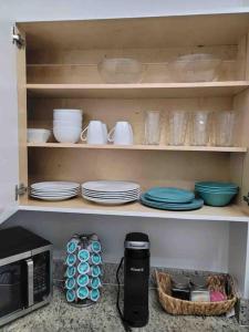 estante de cocina con platos y cuencos y microondas en NEWLY Renovated condo 5 min from Airport en Miami
