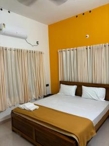 a bedroom with a large bed with yellow walls at Bliss on the Bay in Varkala