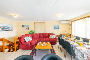 a living room with a red couch and a table at 3 Tomaree Street - Spacious 4 bedroom house with air con situated in the heart of Nelson Bay in Nelson Bay