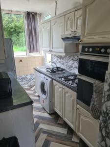 a kitchen with a stove and a washing machine at L & J ESCAPES-4 BEDROOMs SUITABLE FOR CONTRACTORS AND FAMILIES- LARGE PRIVATE PARKING-10 MINUTES TO M6 JUNCTION 9 in Coseley