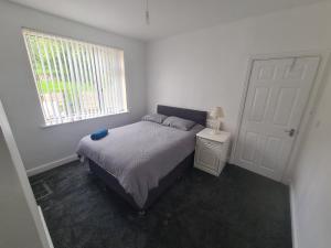 a white bedroom with a bed and a window at L & J ESCAPES-4 BEDROOMs SUITABLE FOR CONTRACTORS AND FAMILIES- LARGE PRIVATE PARKING-10 MINUTES TO M6 JUNCTION 9 in Coseley
