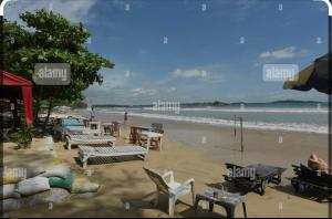 a beach with chairs and tables and the ocean at Calm Palace in Weligama