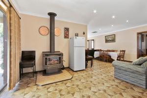 a living room with a fireplace and a refrigerator at Family Escape in Lakes Entrance