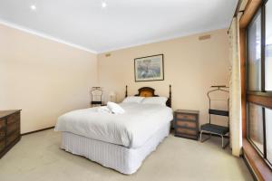 a bedroom with a large white bed and a window at Family Escape in Lakes Entrance