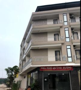 ein hohes Gebäude mit einem roten Schild davor in der Unterkunft Quỳnh Hương Hotel Phú Thọ in Phú Thọ