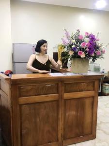 a woman sitting at a desk with flowers at Quỳnh Hương Hotel Phú Thọ in Phú Thọ