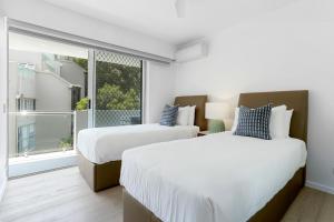 two beds in a room with a window at The Cove Noosa - Apartment 9 in Noosa Heads