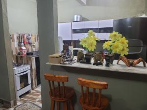 a kitchen with two chairs and a counter with flowers on it at Casa de praia in Goiana