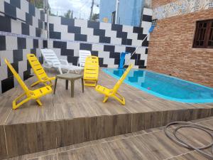 a group of yellow chairs and a swimming pool at Casa de praia in Goiana