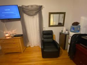 a bedroom with a chair and a dresser with a television at Room in Guest room - 7privateroom Jacuzzimassage Sitparking15mins2ny in North Bergen
