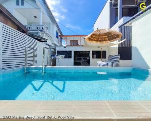 - une piscine avec un parasol et une chaise dans l'établissement GAO Marina Retro Pool Villa, à Ban Phala