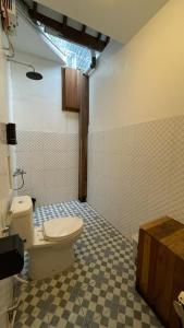 a bathroom with a toilet and a checkered floor at Sampai Villa D'Watu in Beran-kidul +3 photos
