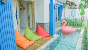 a porch with colorful pillows and a pink flamingo at Sampai Villa D'Watu in Beran-kidul