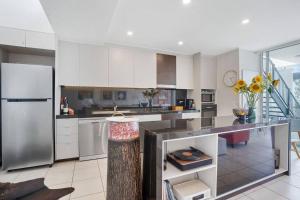 a kitchen with white cabinets and a stainless steel refrigerator at Lookout 334 - Endless Ocean Views - Rooftop Spa in Kingscliff