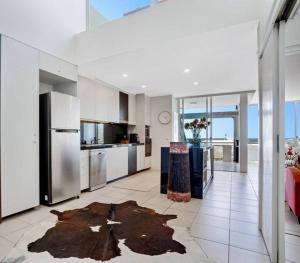a kitchen with stainless steel appliances and a large room at Lookout 334 - Endless Ocean Views - Rooftop Spa in Kingscliff