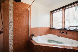 baño con bañera y ventana en Homestead Loft- Private retreat, amongst the gums with woodfire and spa bath, en Wallington