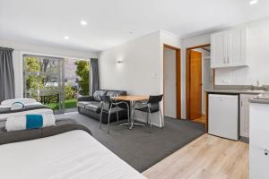 Cet appartement comprend une chambre avec un lit et une cuisine avec une table. dans l'établissement ASURE Brookvale Motel, à Wanaka