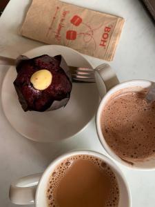 einen Teller mit einem Muffin und zwei Tassen Kaffee in der Unterkunft LOVE LODGE BRINCHANG, CAMERON HIGHLANDS in Tanah Rata