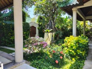 a garden with flowers in front of a house at Villa Frangipani in Sanur