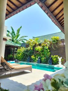 a patio with a swimming pool and a chaise lounge at Villa Frangipani in Sanur
