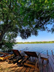 ein Picknicktisch und Stühle auf einer Anlegestelle neben einem See in der Unterkunft Boletov raj lux in Čurug