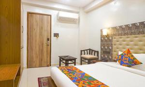 a bedroom with a bed and a desk and a door at FabHotel Palash in Dānāpur