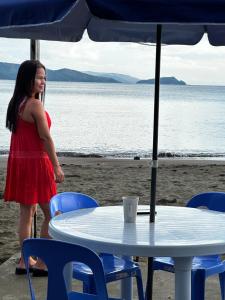 een vrouw in een rode jurk aan een tafel op het strand bij Azure at Tranquility Bay Beach Resort in Kinabutan