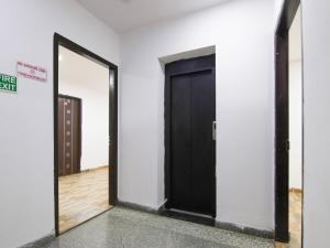 een zwarte deur in een witte kamer met een spiegel bij RD HOTEL in New Delhi
