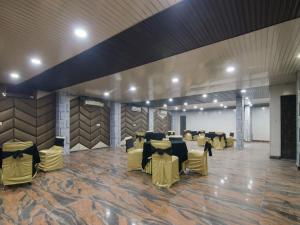 een grote feestzaal met tafels en gele stoelen bij RD HOTEL in New Delhi