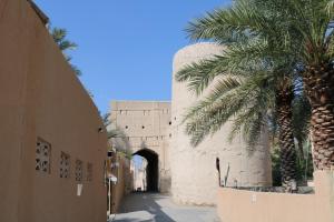 a street with palm trees and a building with a tunnel at Riad Nizwa in Nizwa