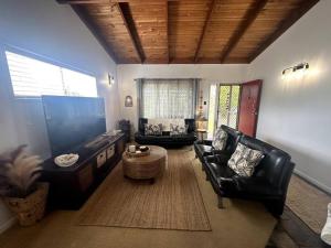 a living room with black leather chairs and a table at Palm Breeze - 4 bedroom -Walk to the beach in Bargara