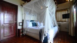 1 dormitorio con cama con dosel y cortinas blancas en Last Frontier Beach Resort-Adults Only en El Nido