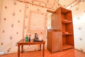 Habitación con mesa de madera y nevera. en Shama Desert Camp & Resort, en Sām