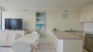 cocina con encimera, TV y mesa en Boulevard North Holiday Apartments, en Gold Coast