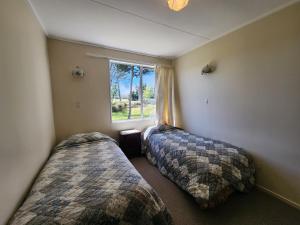 two beds in a room with a window at Manapouri Holiday Park in Manapouri