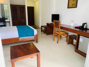a bedroom with a bed and a desk and a desk at Hotel Gangaaddara in Kandy