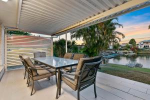 a table and chairs on a patio with a view of the water at Happiness On Hoya in Bongaree