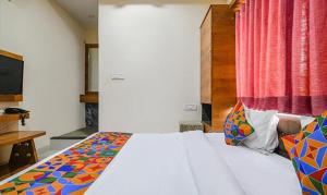 a bedroom with a white bed with a colorful blanket at FabHotel Royal Palace in Indore