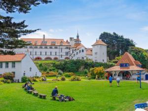 people sitting on benches in a park in front of a castle at Rias Cottage in Landshipping