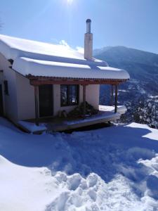 une maison dans la neige avec de la neige sur le toit dans l'établissement Ορεινή μονοκατοικία στα Χαλκιάνικα - Κοντά στη Ζαρούχλα - λίμνη Τσιβλού, à Khalkiánika