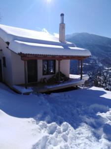 a house in the snow with snow on the roof at Ορεινή μονοκατοικία στα Χαλκιάνικα - Ζαρούχλα - λίμνη Τσιβλού in Khalkiánika