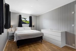 ein Schlafzimmer mit einem Bett mit einer Kommode und einem Fenster in der Unterkunft beautiful villa with seaview and sunny in Askøy