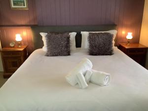 two towels on a white bed with two lamps at Rosellas on Corundum Cottage - treat yourself! in Stanthorpe