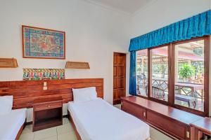 a bedroom with two beds and a window with a balcony at Capital O 93236 Hotel Hapel Negara in Banyubiru