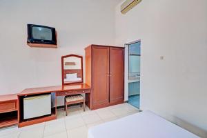 1 dormitorio con escritorio, TV y cama en Capital O 93236 Hotel Hapel Negara en Banyubiru