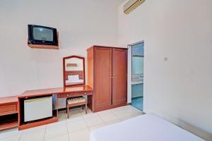 a bedroom with a desk and a tv and a bed at Capital O 93236 Hotel Hapel Negara in Banyubiru