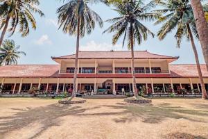 ein Gebäude mit Palmen davor in der Unterkunft Capital O 93236 Hotel Hapel Negara in Banyubiru