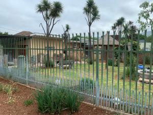 einen Zaun vor einem Garten mit Palmen in der Unterkunft Nonesi Lodge 2 in Queenstown